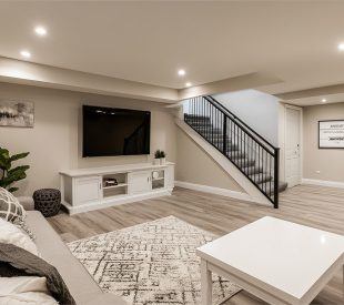 An interior shot of a recently renovated basement with contempor An interior shot of a recently renovated basement with contemporary design elements, including a large white sectional sofa and gray-toned wood-look flooring