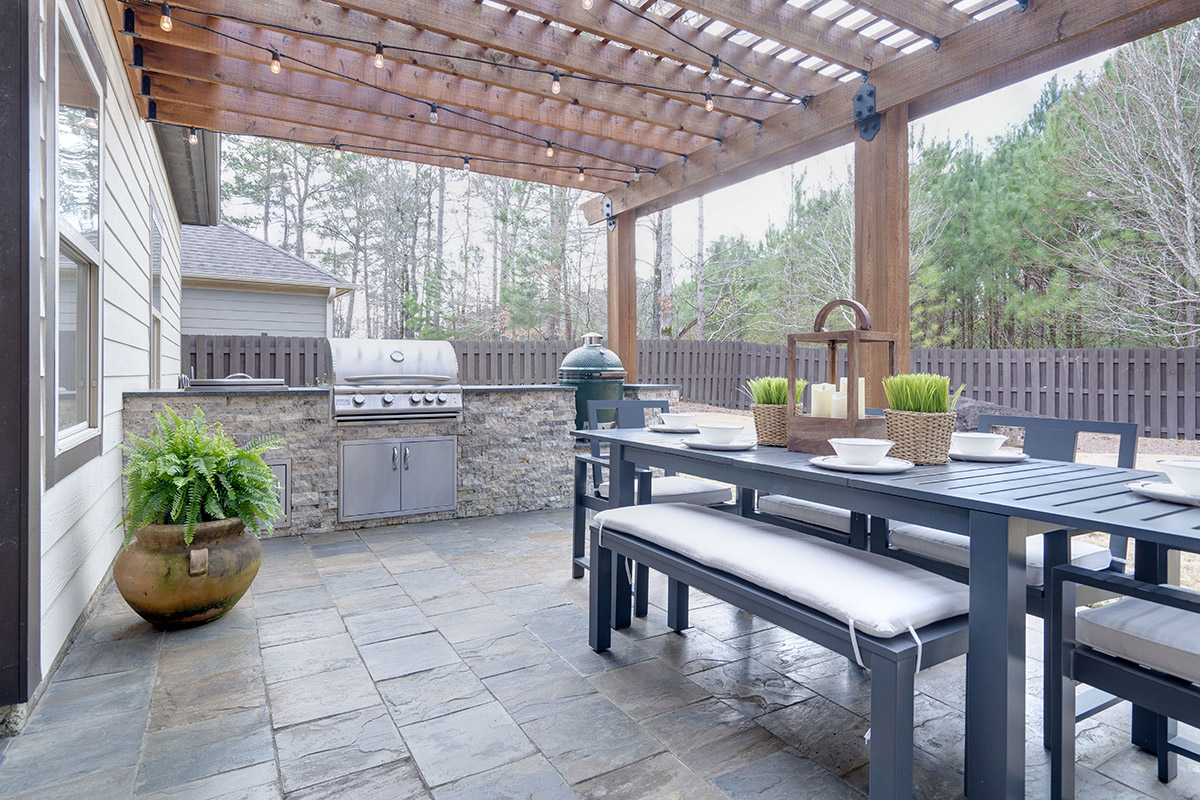 Pretty summer outdoor kitchen with table set and grilling statio